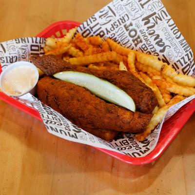 Deep fried boneless, chicken breasts, with pickles, fries, and dip.