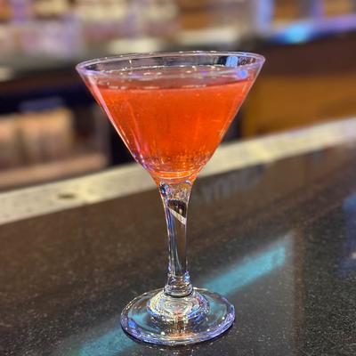 Red cocktail in a martini glass on the counter.