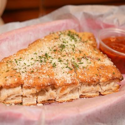 Bread sticks topped with parmesan and parsley, served with a dip.