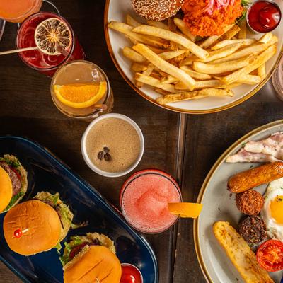 An overhead view of colorful cocktails and plates of food.