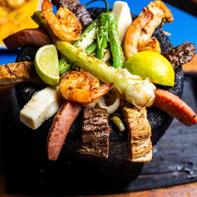 Molcajete dish with grilled chicked, beef, shrimp and vegetables.