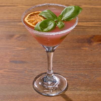 Strawberry Lemon Drop Martini garnished with a dry orange wheel and basil.