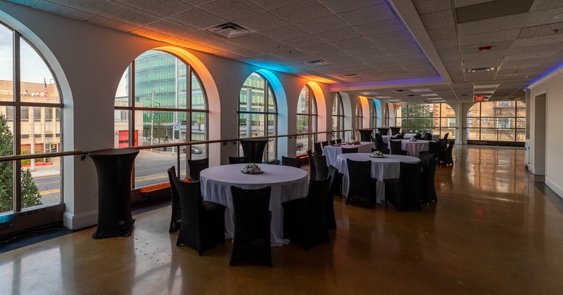 Interior, dining area, round white cloth tables for eight, large arched windows