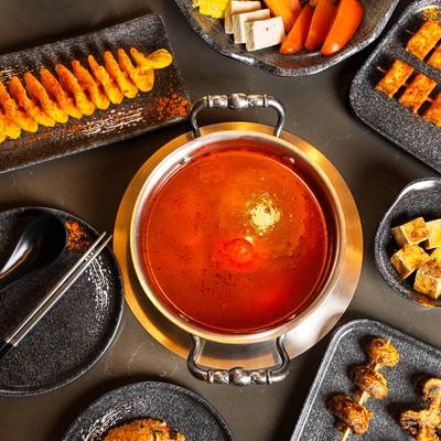 Overhead view of a hot pot meal with a pot of simmering broth surrounded by appetizers.