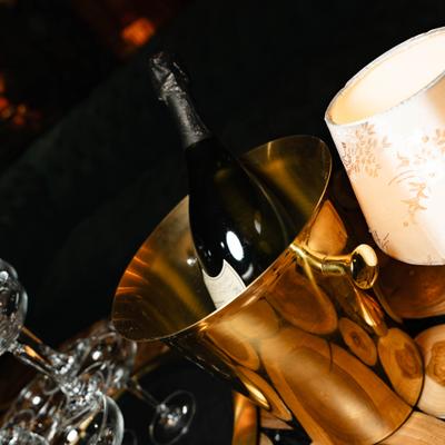 Champagne bucket on a table with empty glasses and a lamp.