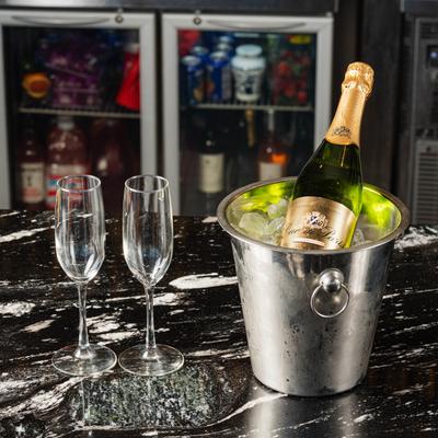 A bucket with sparkling wine and two champagne glasses on bar counter.