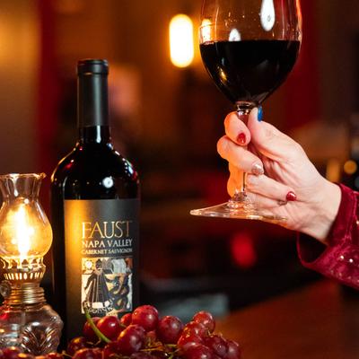 A hand holding a glass of wed wine.