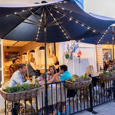 An outdoor restaurant patio with people dining under large umbrellas.