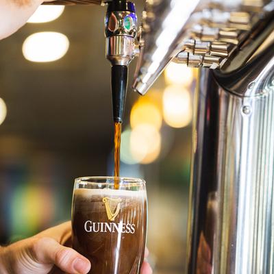 Hands pouring dark beer from the dispensary