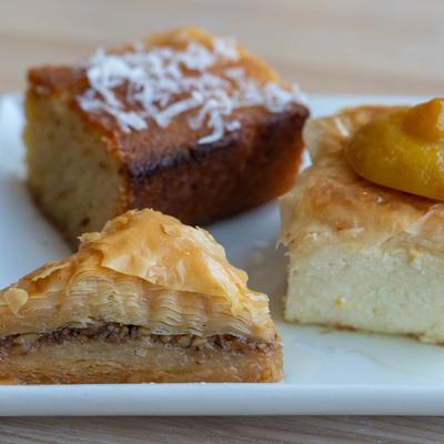 Dessert plate with baklava, semolina cake, and custard pastry.