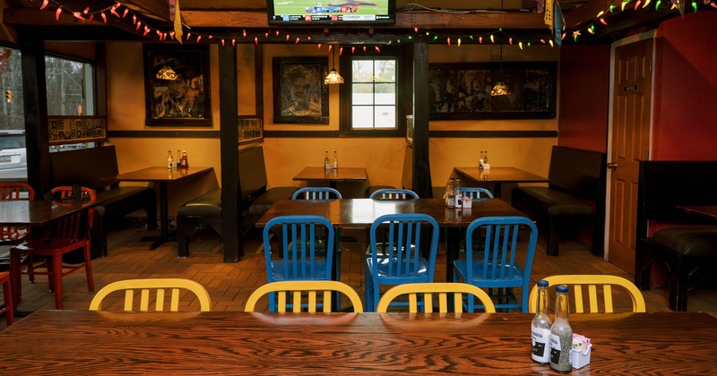 Mexican-style dining area with wooden tables and chairs and booths along the wall