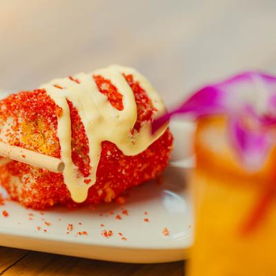 Mexican street corn topped with powdered chili pepper and creamy sauce drizzle.