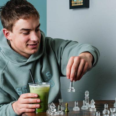 A person holding a drink and playing chess.