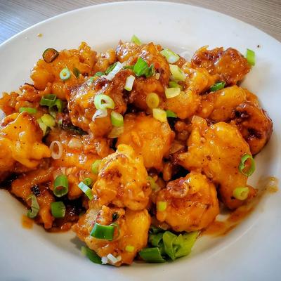 Crispy cauliflower bites with chili sauce and scallions.