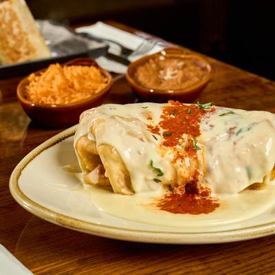 Breakfast Burrito topped with cheese sauce and sour creme, served with rice and beans.