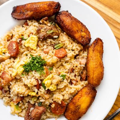 A serving of Cuban style fried rice with sausage and a side of plantains.