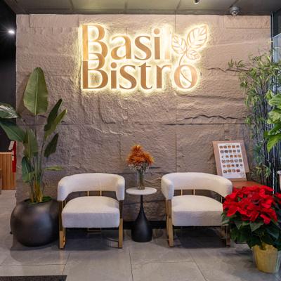 Restaurant's waiting area with two upholstered chairs and illuminated sign.