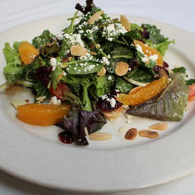 Mixed greens salad with orange slices, almonds, and goat cheese.