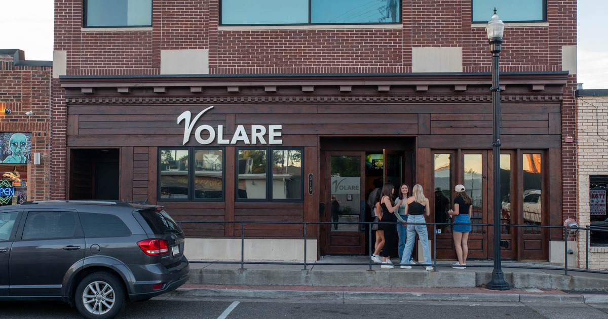 Storefront with signage, people hanging out by the entrance