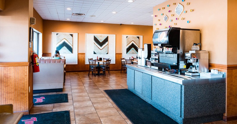 Interior, soda fountain and coffee pouring station, dining area in the back, tile flooring