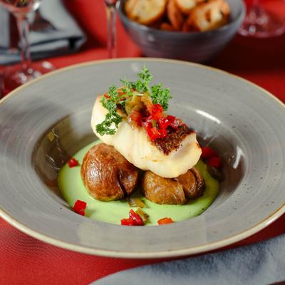 Seared fish served over baked potatoes and a green pureed sauce.