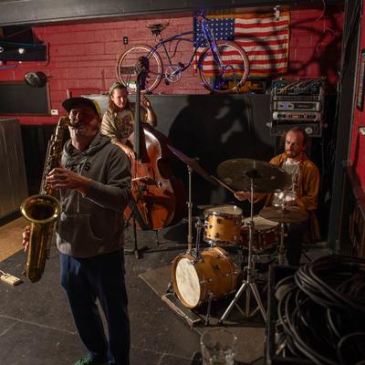 Jazz trio performing on stage with an American flag.