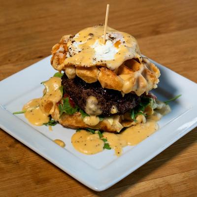 Waffle burger, with steak, bacon jam, brie, tomatoes, arugula, egg, and mornay sauce.