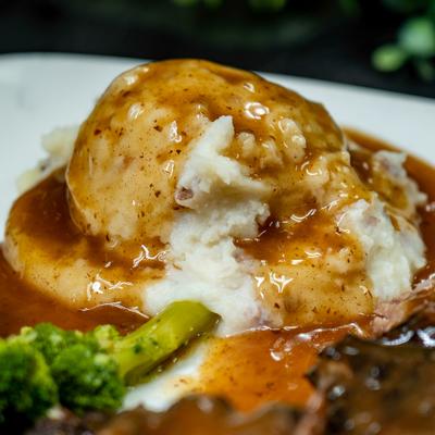 Roast Beef Dinner with side of mashed potatoes topped with gravy, close-up.