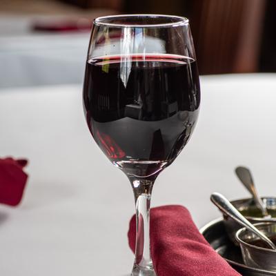 A glass of red wine on a dining table.