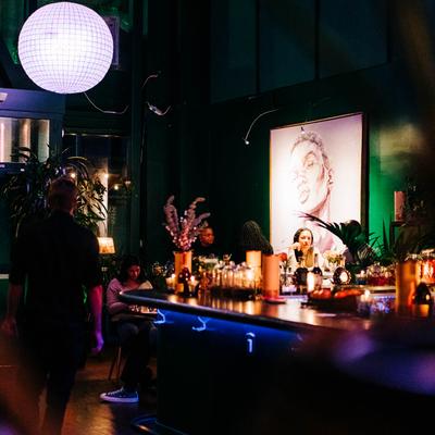 Dimly lit bar with a disco ball, mural, and guests.