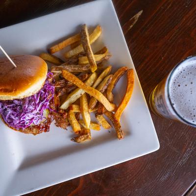 Pulled pork sandwich, with red cabbage, pickles, sauce and a side of fries photo.