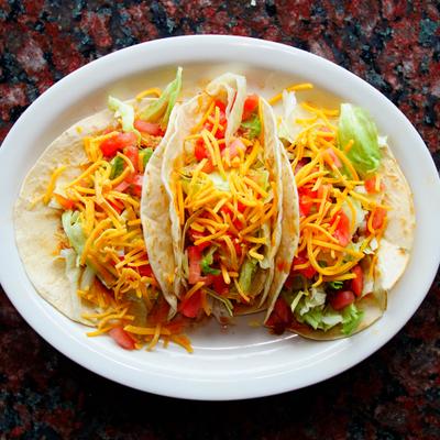 Mexican Style Tacos topped with fresh cilantro, onions and shreded cheese.