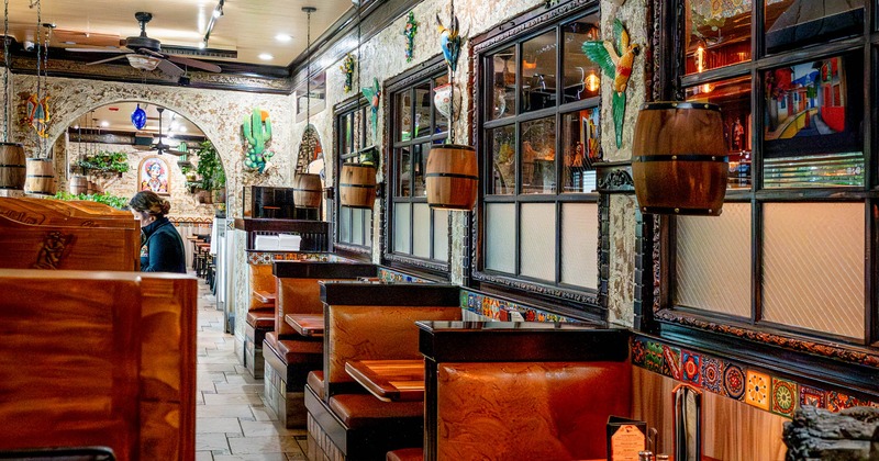 Restaurant interior with wooden booths, decorative tiles, and hanging barrel-shaped lights