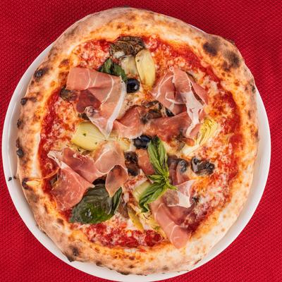 Prosciutto pizza, with tomato sauce, mozzarella, artichokes, mushrooms, olives, and EVOO