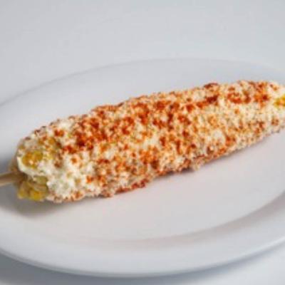 Corn on the cob covered in a creamy sauce, served.