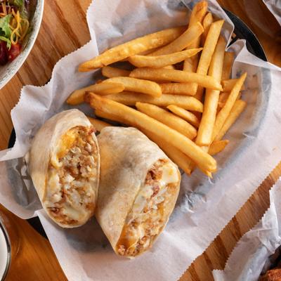 Junkyard wrap sliced in half and served with a side of fries.