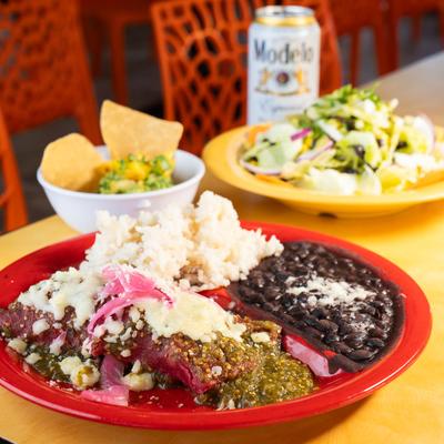Enchilada Suizas plate, guacamole with pineapple, Boda salad and a beer can.