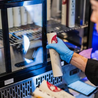 Staff member taking wraped sushi rolls feom the refrigerator.