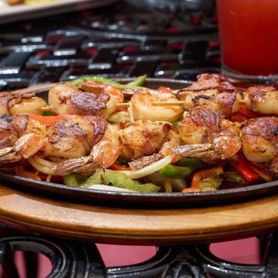 Grilled shrimp with onions and peppers on a skillet.