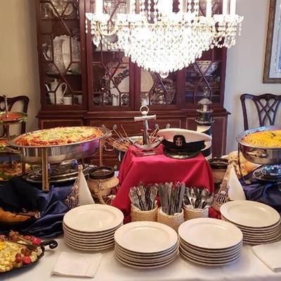 Buffet table with Italian food, naval theme decorations, plates, and utensils.