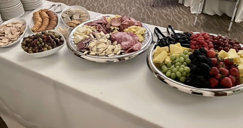 Buffet table with fruit, cheese, meats, crackers, and olives