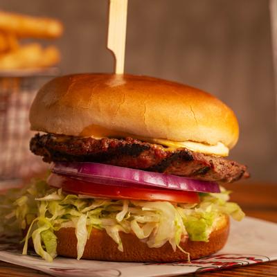 Cheeseburger with lettuce, tomato, and onion on a toasted bun.