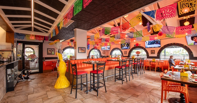 Lively Mexican-style restaurant interior, dining area decorated with hanging paper ornaments