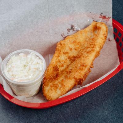 Fried tilapia fish served with coleslaw in a pepper-lined red basket.