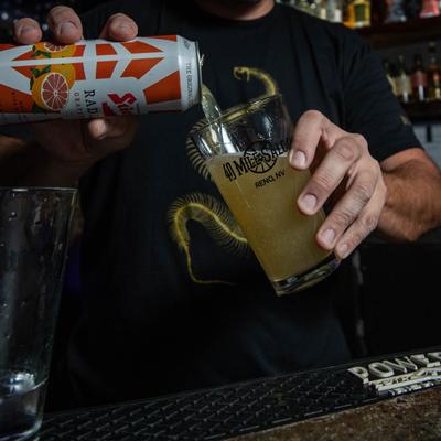 Hands pouring a drink from a can.