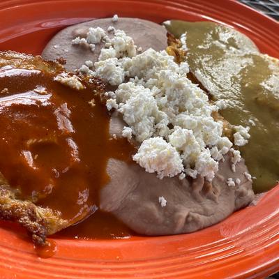 Two sauced potato slices with refried beans topped with cheese.