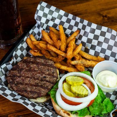Burger with onions, tomatoes, lettuce, and pickles, served with fries.