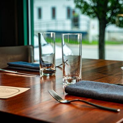 Dining table, with glasses, utensils, and anpkins.