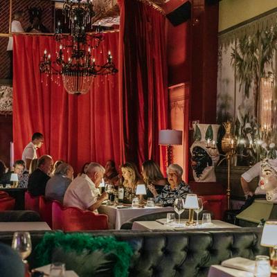 Full dining room with guests seated at every table beneath chandeliers.