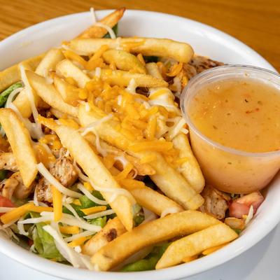 Grilled chicken salad with a dressing on the side.